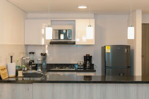 A modern kitchen with a central island, a built-in oven, a refrigerator, and pendant lighting. - Apto moderno en Serena con balcon  (Cartagena)