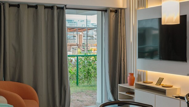 A modern room with a TV, a dining area, and a view of buildings and greenery outside. - Apto moderno en Serena con balcon  (Cartagena)
