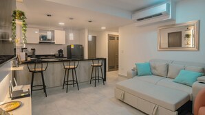 A modern kitchen with bar stools, a sofa, and a mirror. - Apto moderno en Serena con balcon  (Cartagena)