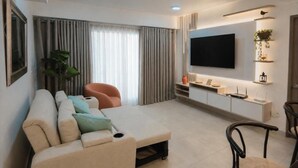 A modern living room with a sofa, a TV, and a plant. - Apto moderno en Serena con balcon  (Cartagena)