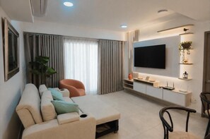 A modern living room with a sofa, a TV, and a plant.