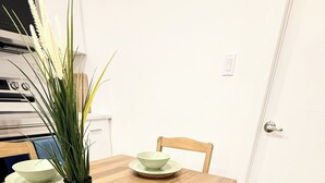 Een eettafel met vier kommen, een potplant en een stoel met een zachte zitting.