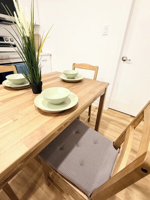 A dining table with four bowls, a potted plant, and a chair with a cushioned seat. - Modern 2BR suite | U of A •Whyte Ave •Downtown (Edmonton)