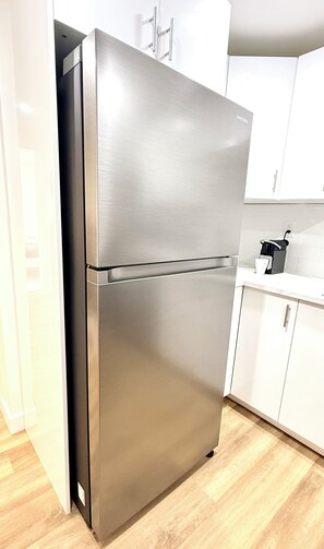 A stainless steel refrigerator in a kitchen with white cabinets and a wooden floor. - Modern 2BR suite | U of A •Whyte Ave •Downtown (Edmonton)