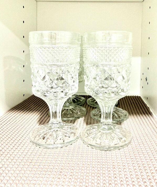 Two clear glass goblets with intricate cut patterns, placed on a textured surface. - Modern 2BR suite | U of A •Whyte Ave •Downtown (Edmonton)