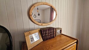 A wooden dresser with a mirror above it, a framed photo, and a row of books. - Quiet 3-room apartment on the garden level in the mountains (Beauvezer)