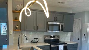Una cocina moderna con una isla central, electrodomésticos de acero inoxidable e iluminación colgante.