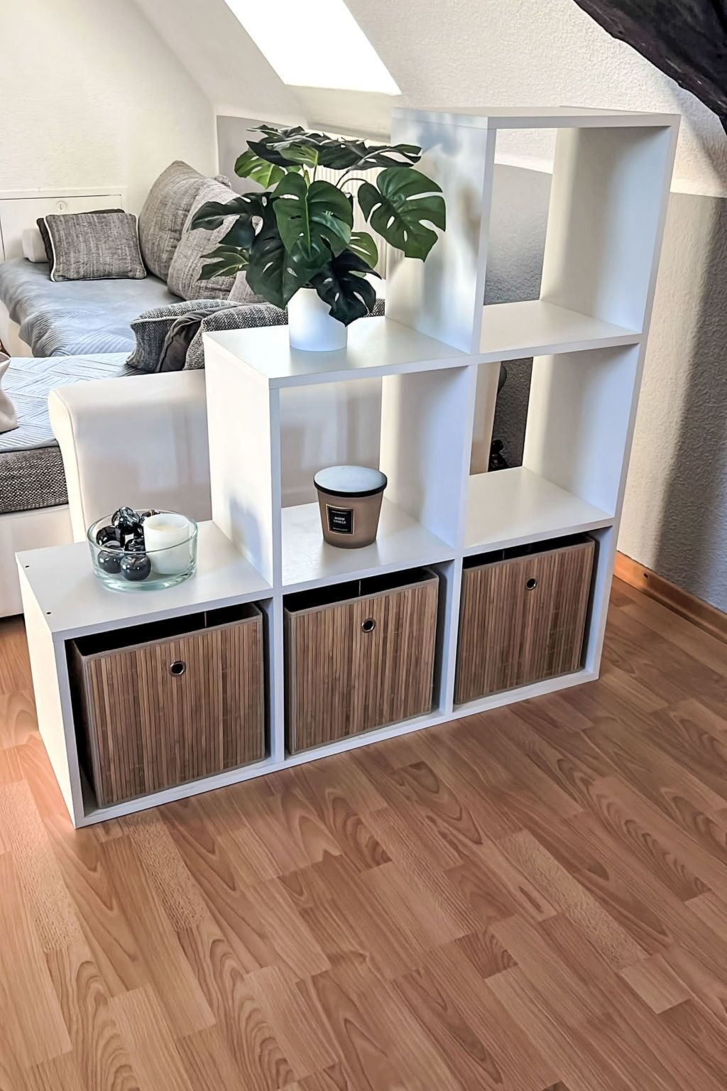 Ein weißes Regal mit einem Blumentopf, einem Glasbehälter und einer Kerze.
