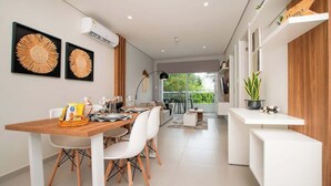 Una cocina moderna con comedor, que incluye una mesa de madera, sillas blancas y dos piezas de arte mural con diseño de sol.