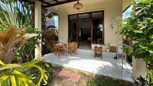 A covered patio with a table and chairs, a potted plant, and a view of the house. - Cozy 1-bedroom bungalow in amazing Ubud with AC (Ubud)