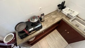 A kitchen with a stove, a kettle, a sink, and a trash bin. - Cozy 1-bedroom bungalow in amazing Ubud with AC (Ubud)