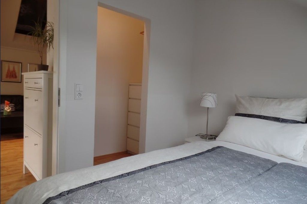 Ein Schlafzimmer mit einem Bett, einem Nachttisch, einer Lampe und einer Kommode.