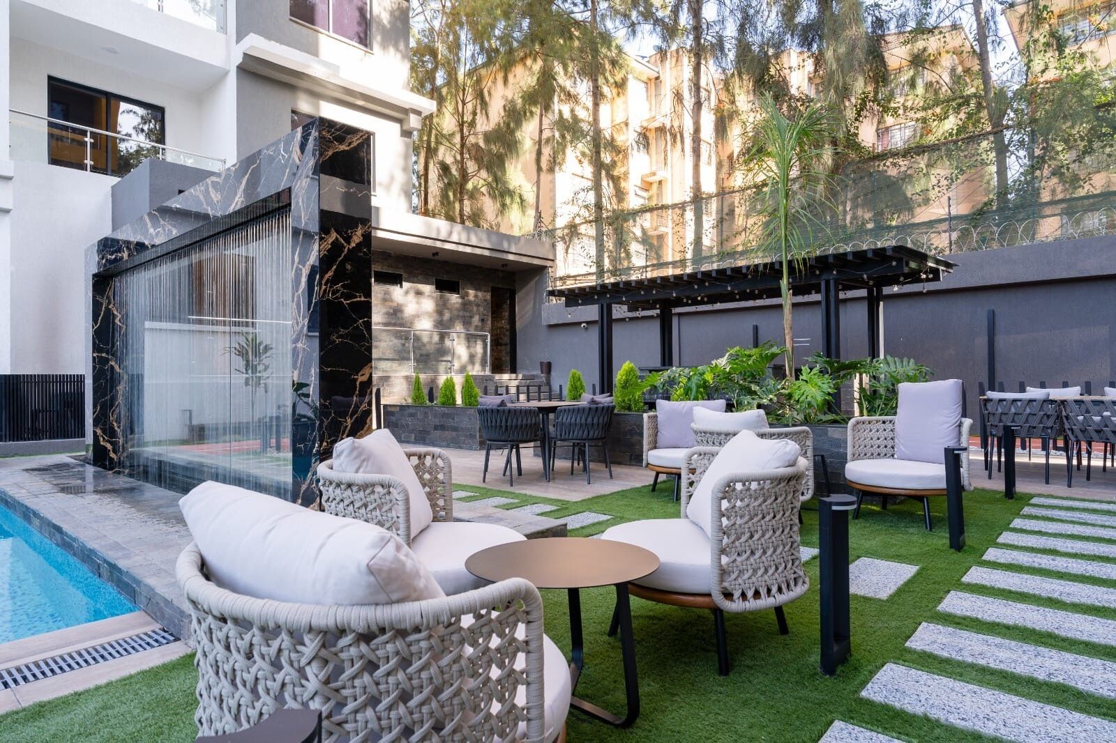 A modern outdoor patio with a pool, seating, and a water feature.