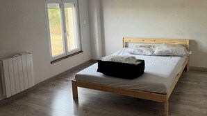 Ein Schlafzimmer mit einem hölzernen Bett, einem Heizkörper, einem Fenster und einer Lampe.