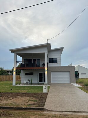 Une maison à deux étages avec un garage, une véranda et un petit jardin.