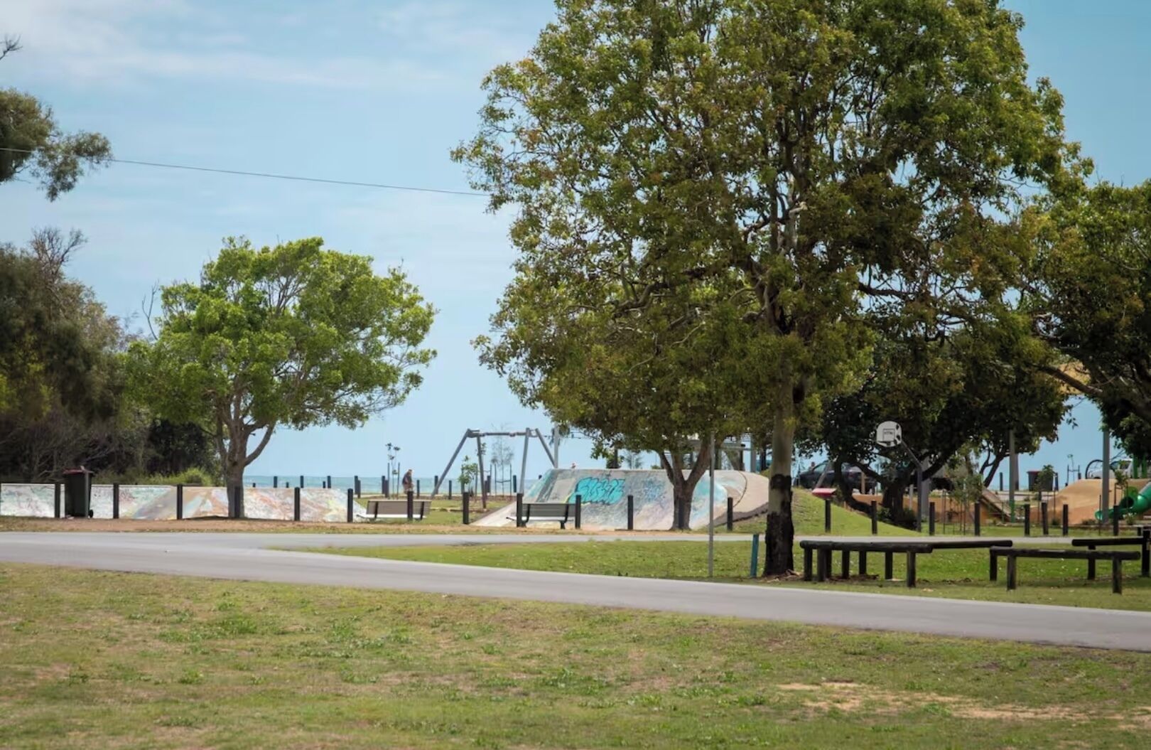 A park with trees, a playground, and a road.