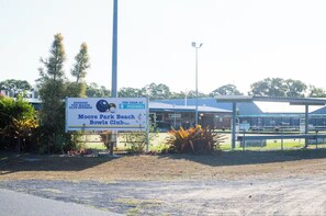 A sign for Moore Park Beach Bowls Club Inc. with a pharmacy nearby.