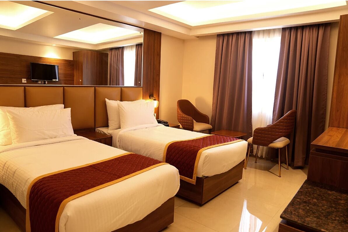 A hotel room with two beds, a flat-screen TV, a chair, and a desk.