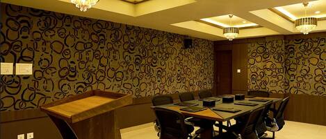 A conference room with a long table, chairs, and a patterned wall.