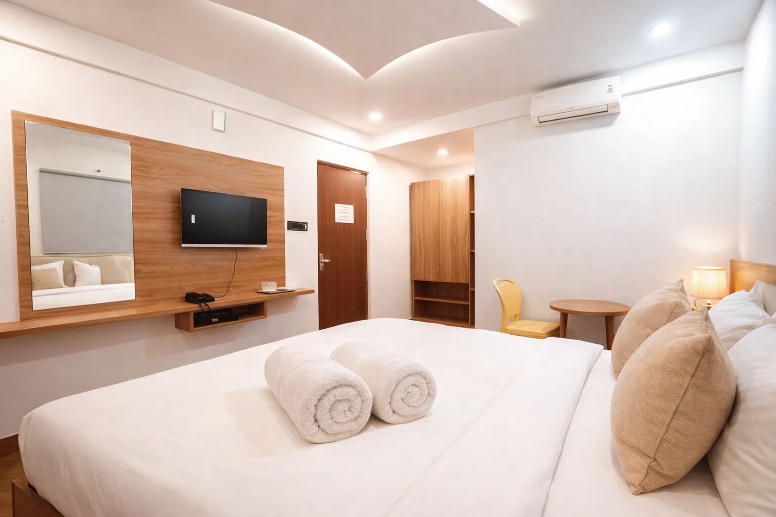 A hotel room with a bed, a TV, a wardrobe, a chair, and a small table.