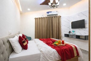 A hotel room with a bed, a TV mounted on the wall, an air conditioning unit, and a breakfast tray on the bed. - Hotel Royal Orbit Near Dronacharya Metro (Gurgaon)