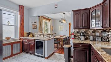 Uma cozinha moderna com armários de madeira escura, bancada de granito e vista para uma sala de jantar.