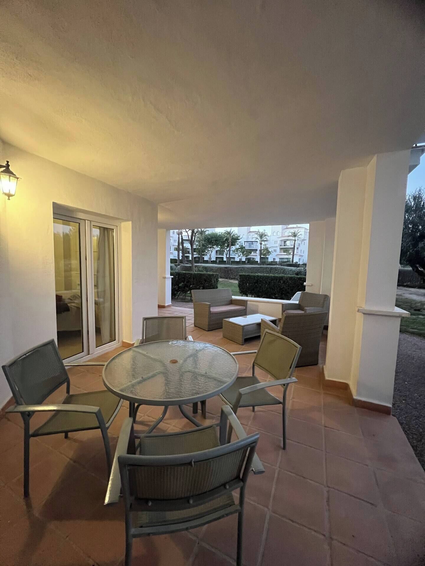 An outdoor patio area with a round glass table, four chairs, and a sofa.