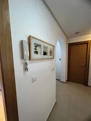 A hallway with a framed picture on the wall, a door, and a light switch. - Adriatico Groundfloor Frontline Golf - 2 Bath - 3 Min Walk to Amenities (Sucina)