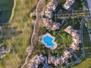 Ett flygbildsbild av ett bostadsområde med en swimmingpool, flera hus och en väg.