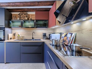 Een moderne keuken met een centraal eiland, geïntegreerde apparatuur en een houten spatwand.
