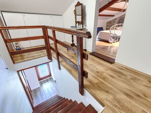 Een houten trap met een leuning die naar een overloop op de tweede verdieping leidt.