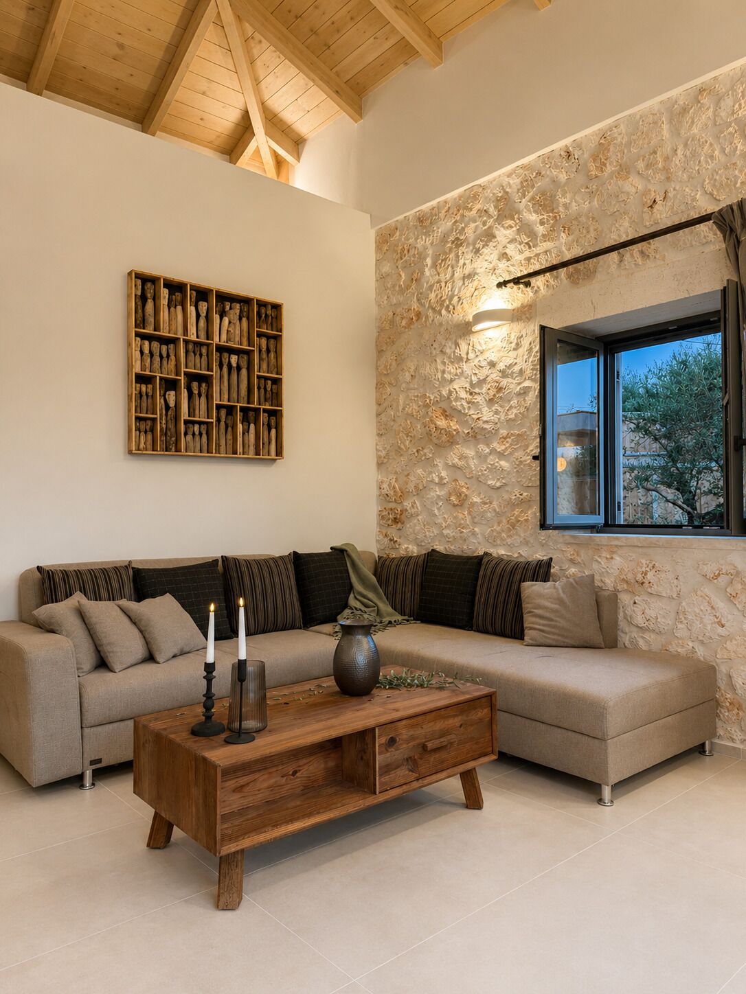 A modern living room with a sectional sofa, a wooden coffee table, a stone accent wall, and a large window with a view.