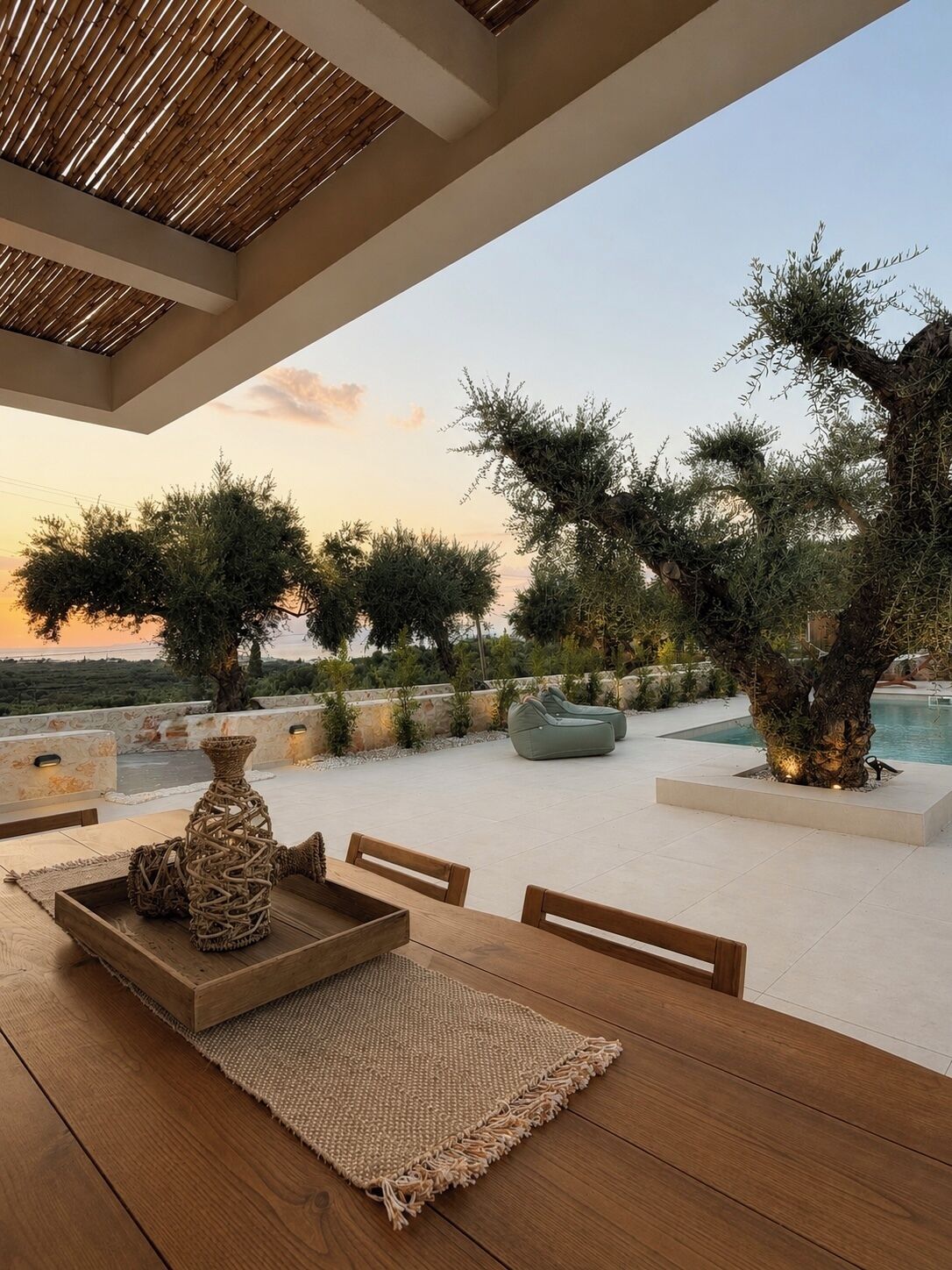 An outdoor seating area with a table, chairs, and a woven rug.