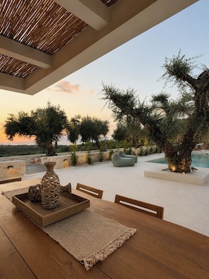 An outdoor seating area with a table, chairs, and a woven rug. - Conte Maris II - Sea View Mediterranean Escape (Tragaki)