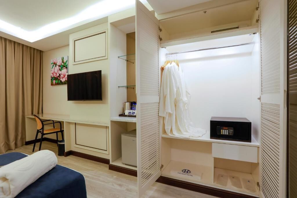 A hotel room with a bed, a desk, a chair, a TV, a wardrobe, and a microwave.