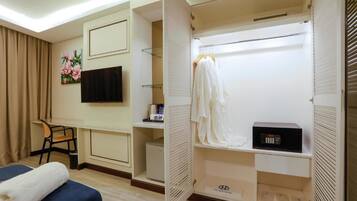 A hotel room with a bed, a desk, a chair, a TV, a wardrobe, and a microwave.
