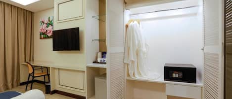 A hotel room with a bed, a desk, a chair, a TV, a wardrobe, and a microwave.