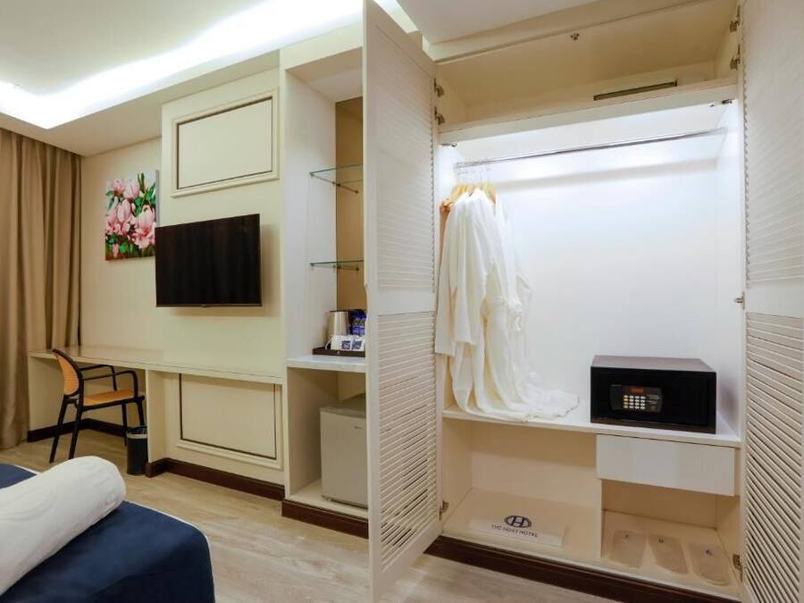 Habitación de hotel con cama, escritorio, silla, televisor, armario y microondas.
