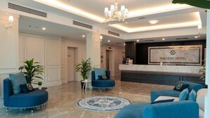 A hotel lobby with a reception desk, blue sofas, a chandelier, and a marble floor. - THE HOST HOTEL (Ipoh)