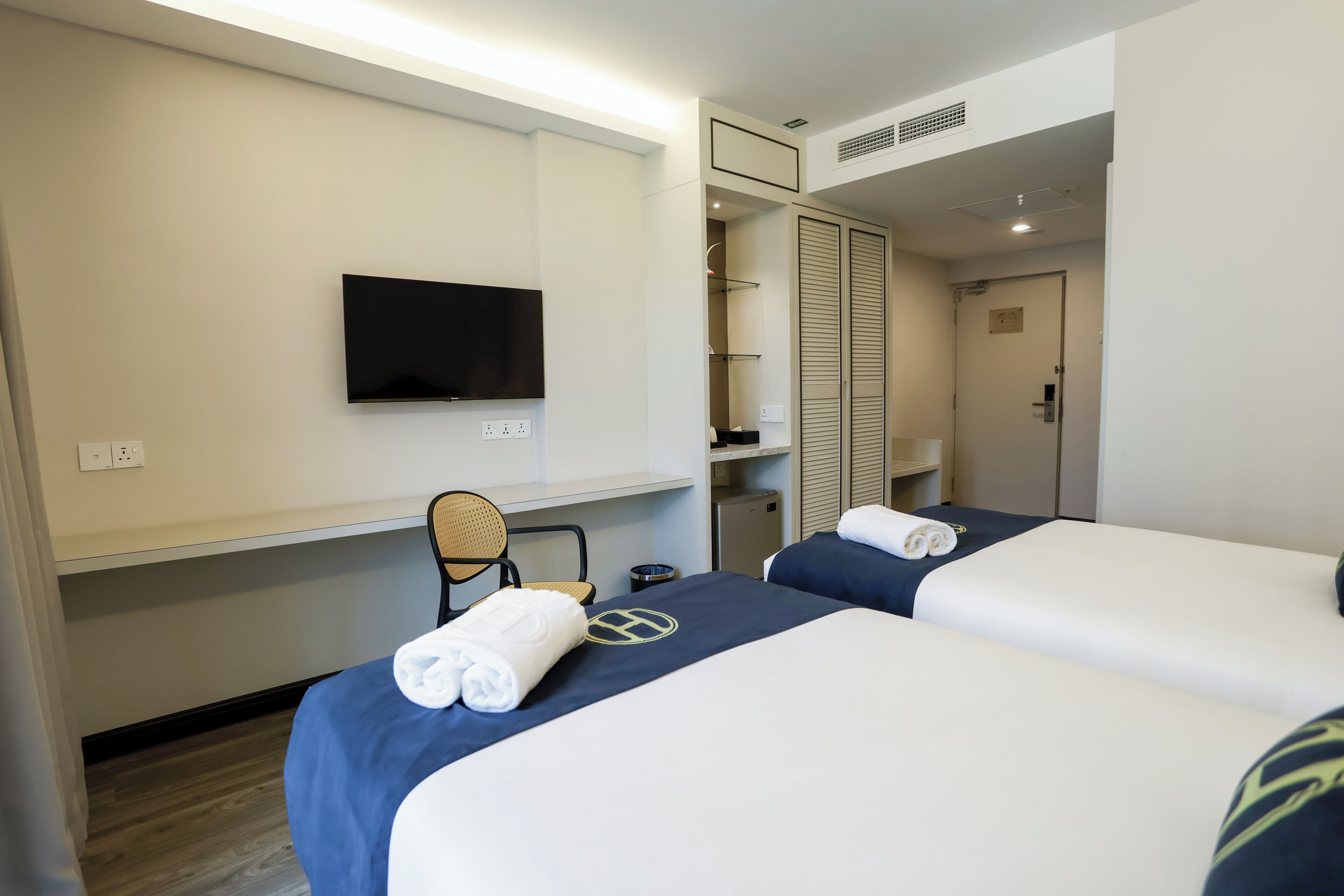 A hotel room with two beds, a TV, a desk, and a wardrobe.