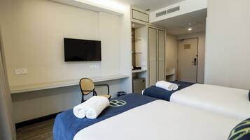 A hotel room with two beds, a TV, a desk, and a wardrobe.