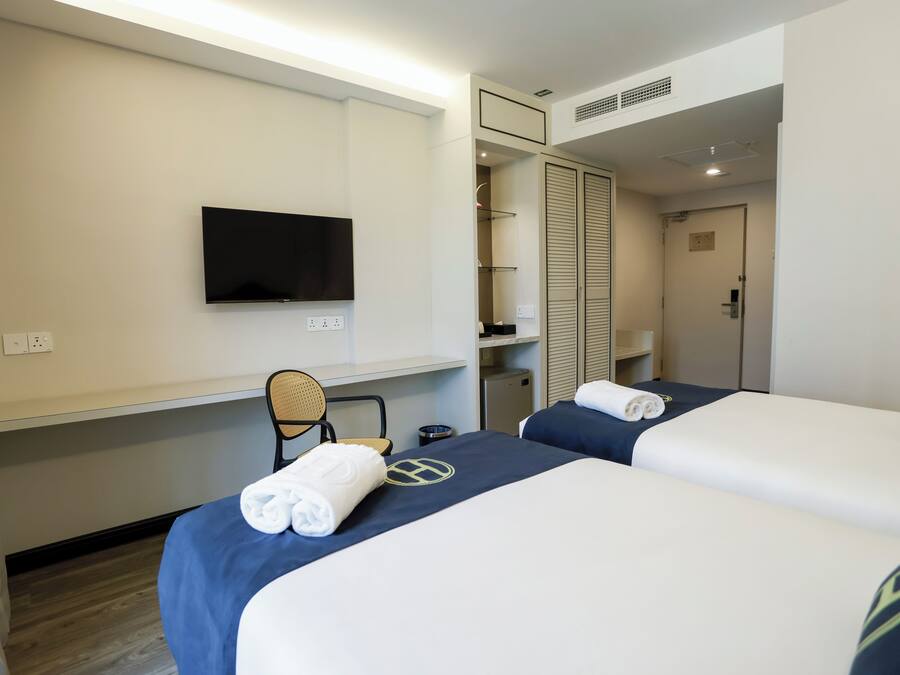 A hotel room with two beds, a TV, a desk, and a wardrobe.