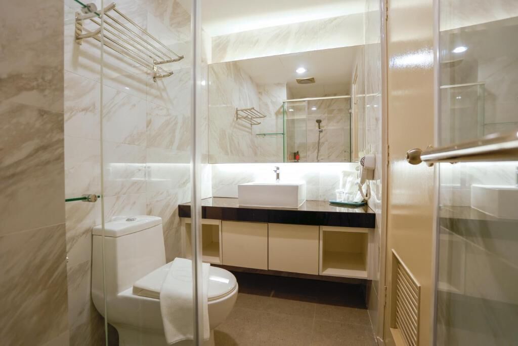 A modern bathroom with a glass shower enclosure, a white toilet, and a marble-tiled wall.
