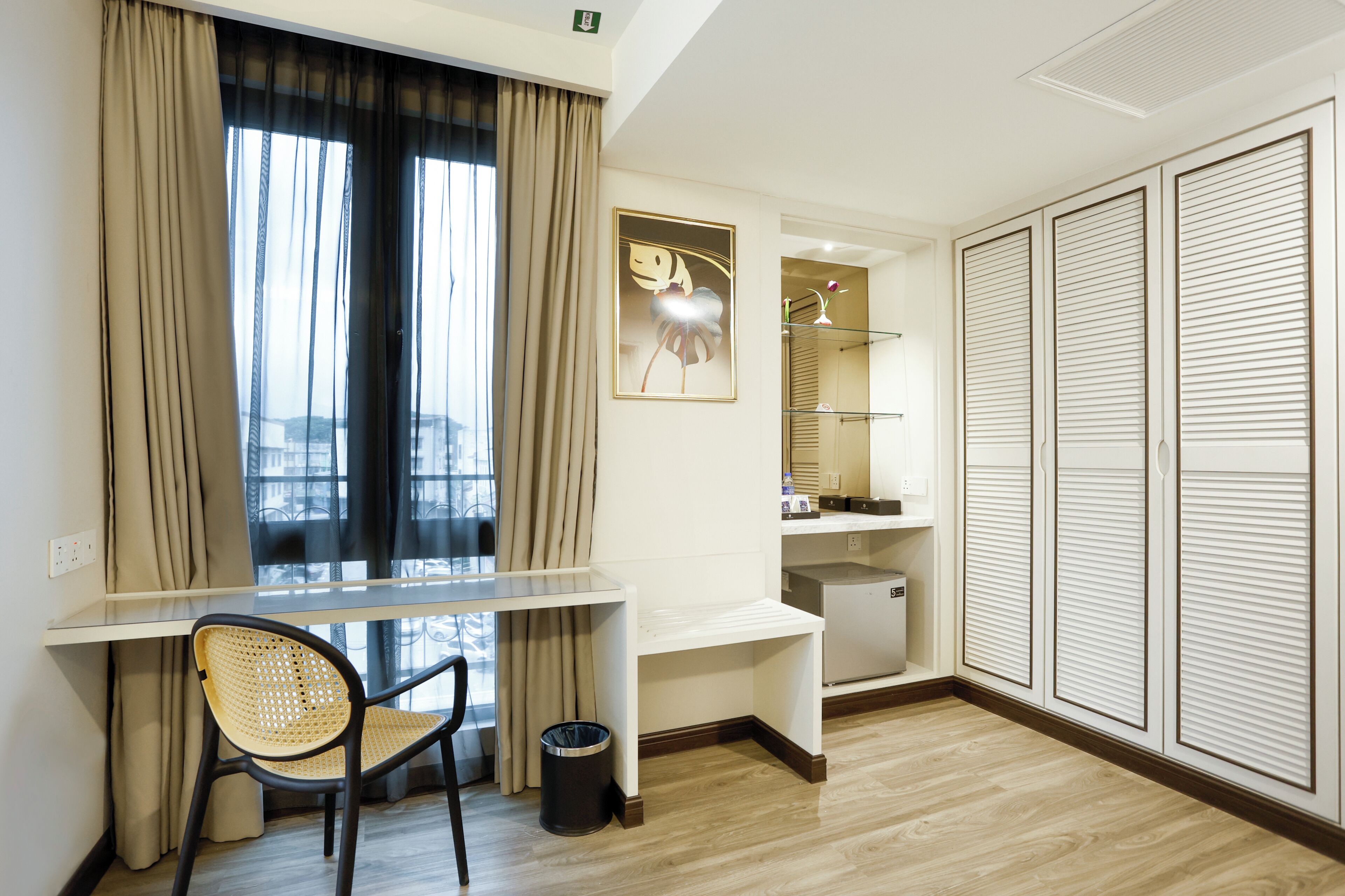A modern room with a desk, chair, wardrobe, and a window with curtains.