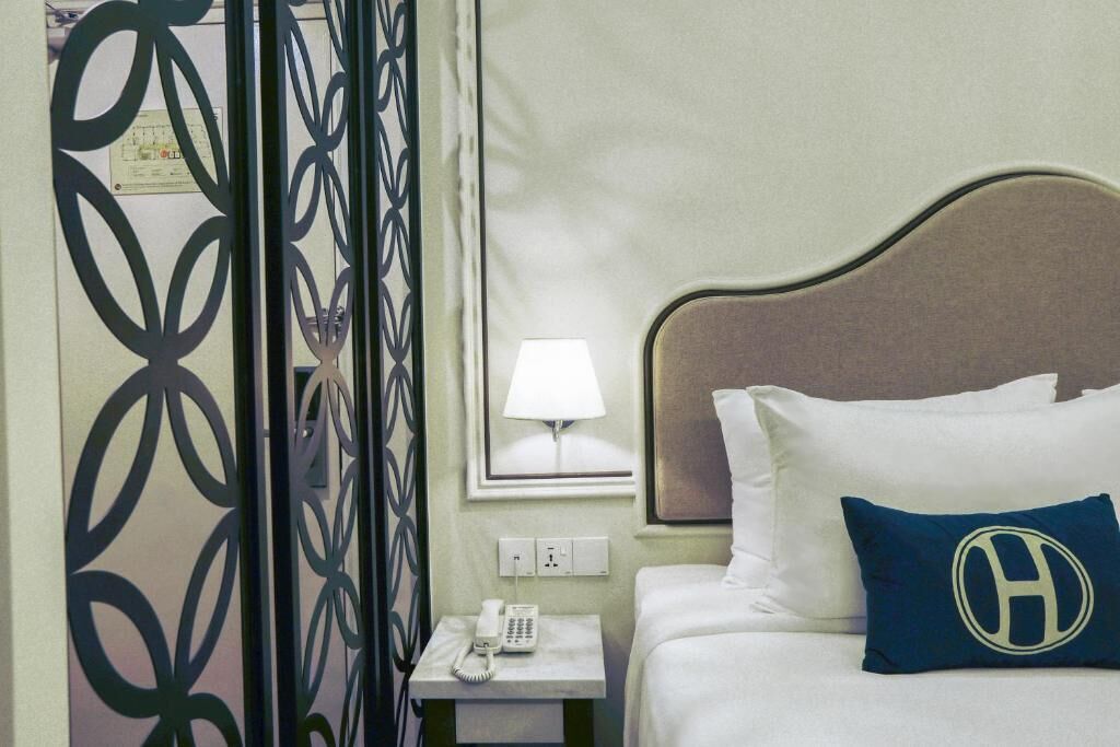 Une chambre d’hôtel comprenant un lit, une table de chevet avec un téléphone, une lampe et un panneau décoratif mural.