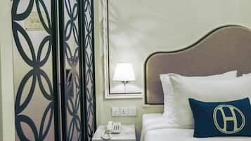 A hotel room with a bed, a nightstand with a phone, a lamp, and a decorative wall panel.