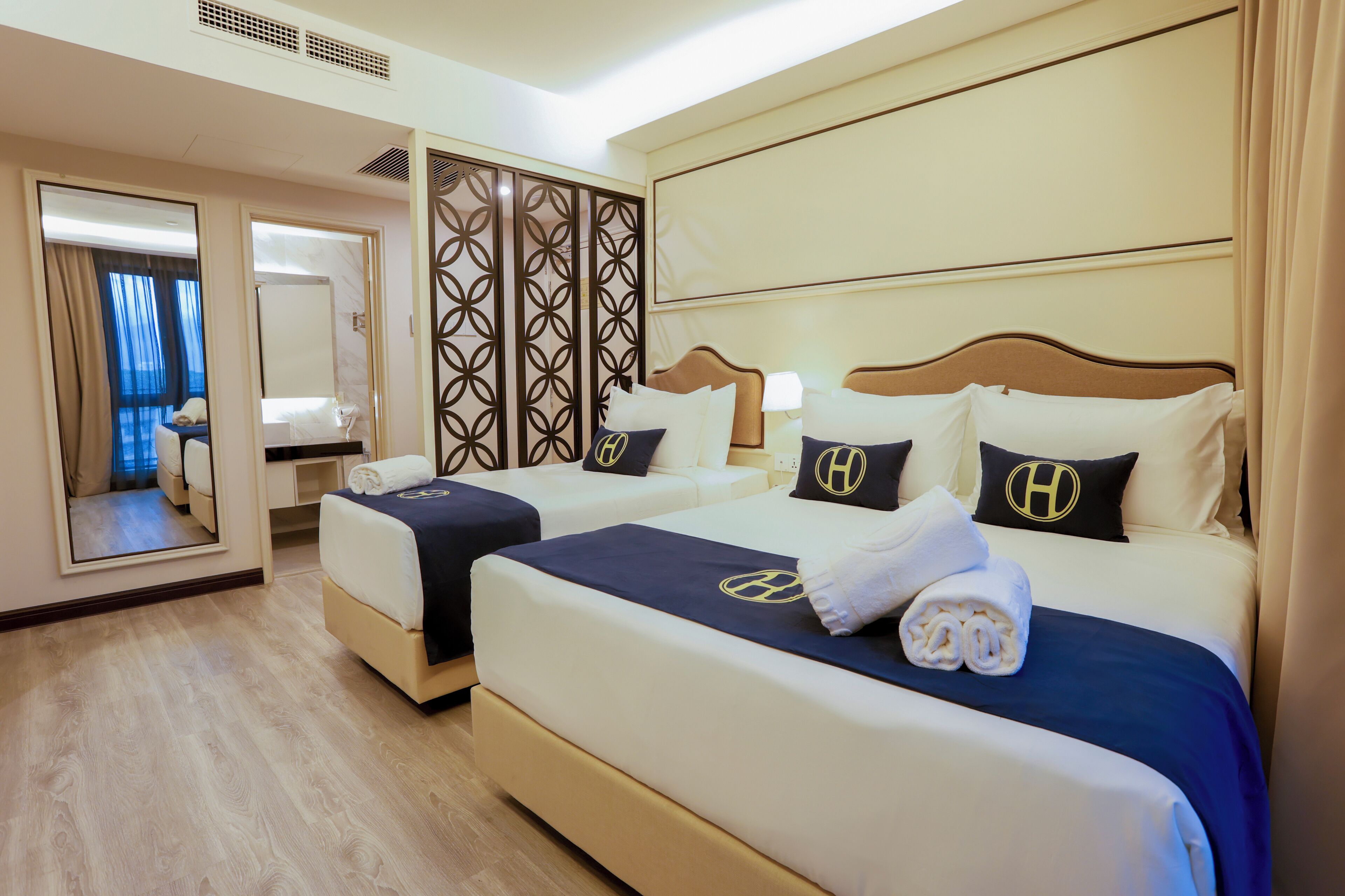A hotel room with two beds, a large mirror, and a view of the sea.