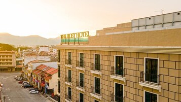 Edificio de hotel con un cartel que dice 'The Host Hotel', múltiples ventanas y un estacionamiento.