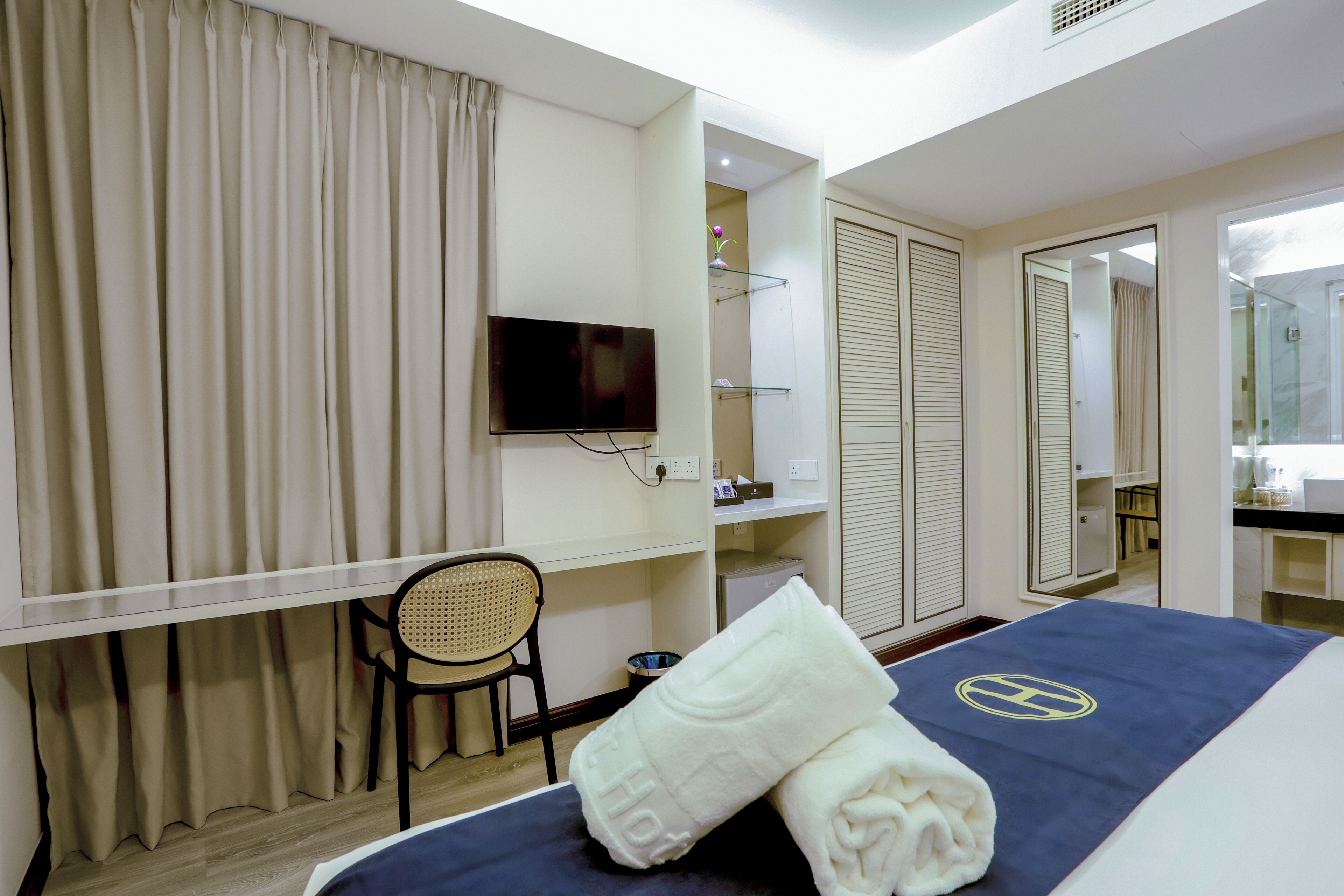 A hotel room with a bed, a television, a chair, a desk, and a bathroom with a mirror and toilet.