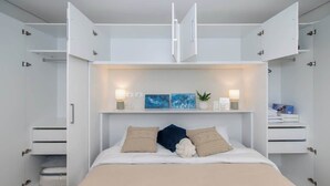 Ein modernes Schlafzimmer mit Bett, Einbauschränken und Nachttischen.
